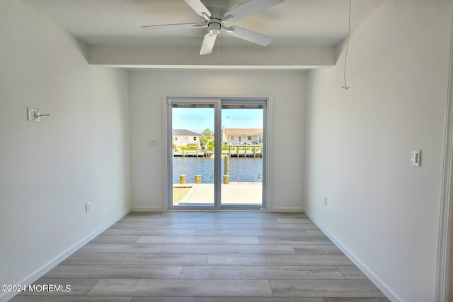 empty room featuring a water view, ceiling fan, and light hardwood / wood-style floors