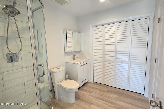 bathroom with a shower with shower door, vanity, wood-type flooring, and toilet