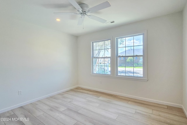 empty room with ceiling fan and light hardwood / wood-style flooring