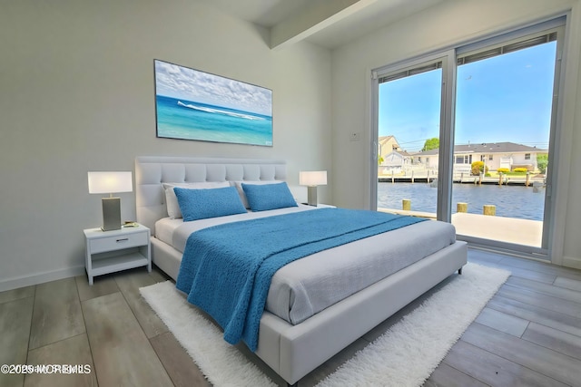 bedroom with access to exterior, beamed ceiling, and a water view