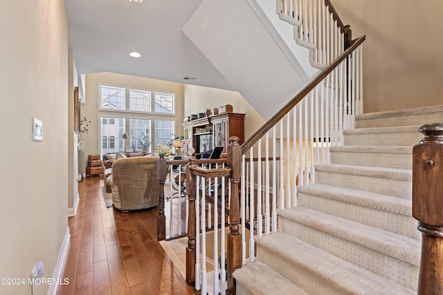 stairs featuring a towering ceiling and hardwood / wood-style flooring