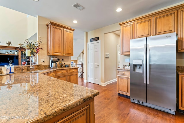 kitchen featuring stainless steel fridge, light stone counters, sink, and dark wood-type flooring