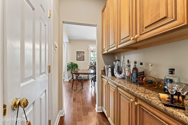 bar featuring light stone counters and dark hardwood / wood-style flooring