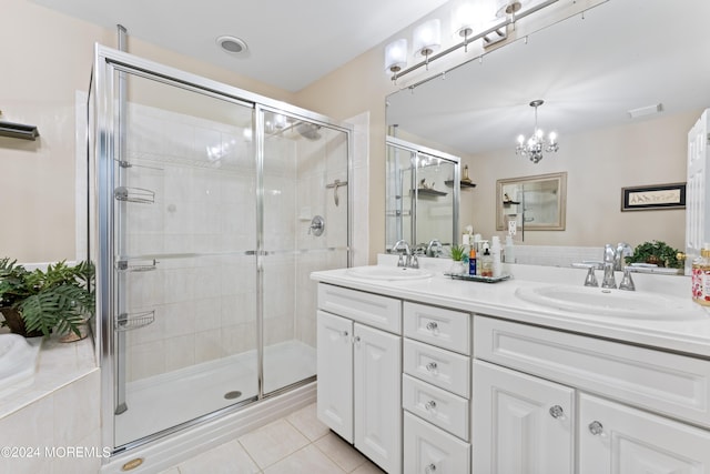 bathroom with tile patterned floors, vanity, an enclosed shower, and an inviting chandelier