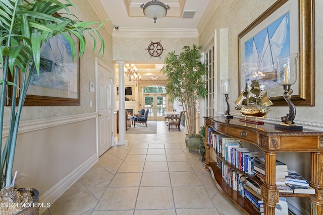 corridor with french doors, ornate columns, ornamental molding, light tile patterned floors, and a notable chandelier