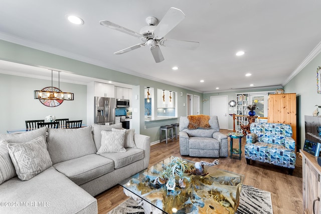 living room with ornamental molding, ceiling fan with notable chandelier, and hardwood / wood-style floors