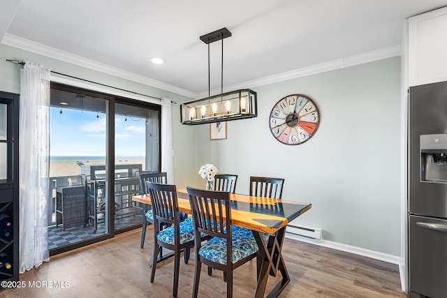 dining area with a baseboard heating unit, ornamental molding, a water view, and hardwood / wood-style floors