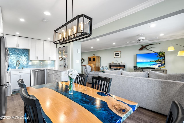 dining space featuring ornamental molding, ceiling fan with notable chandelier, and dark hardwood / wood-style flooring