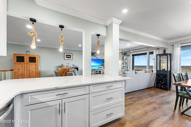 kitchen featuring light stone countertops, pendant lighting, white cabinets, hardwood / wood-style flooring, and crown molding