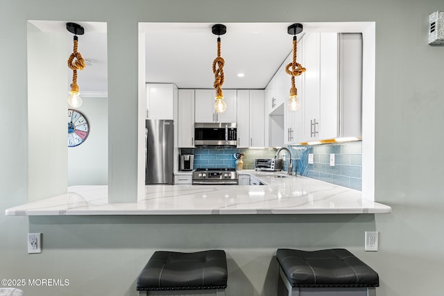 kitchen featuring white cabinetry, appliances with stainless steel finishes, kitchen peninsula, and a breakfast bar area