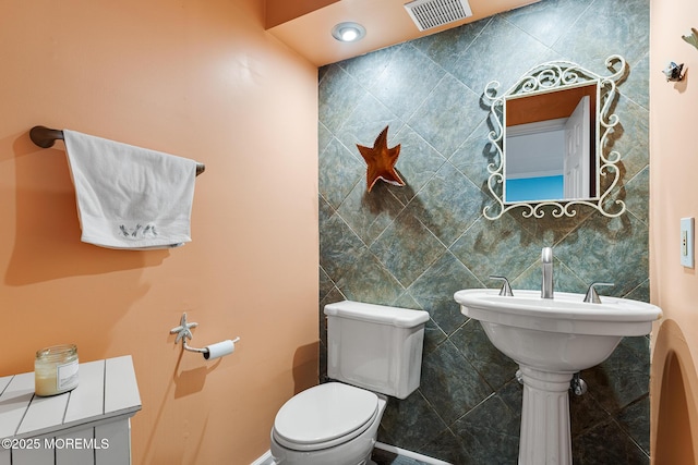 bathroom featuring toilet and tile walls