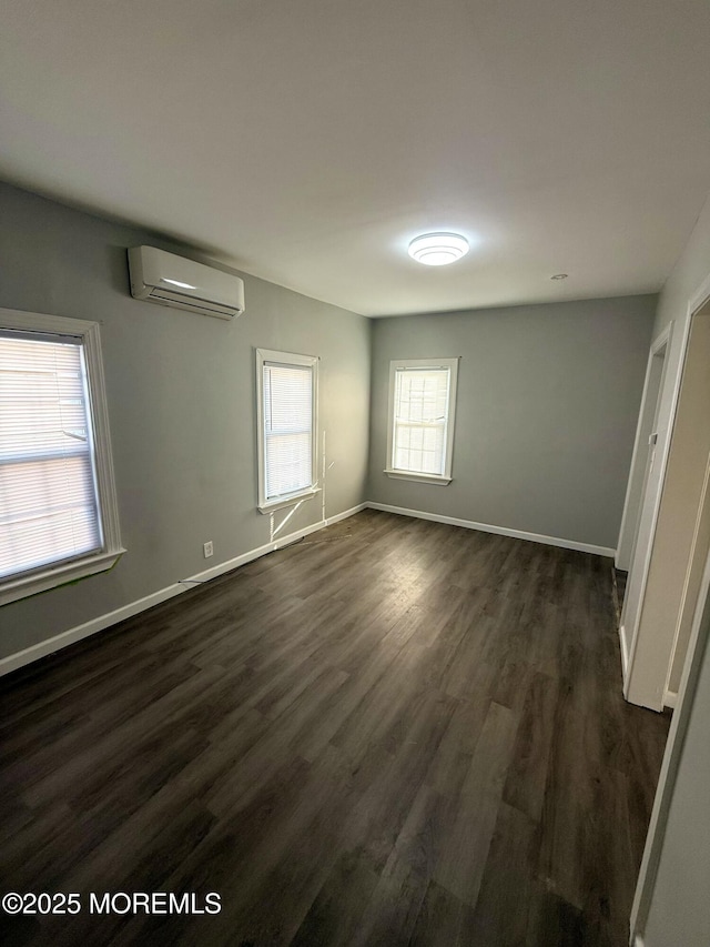 empty room featuring a wall mounted AC, a wealth of natural light, and dark hardwood / wood-style floors