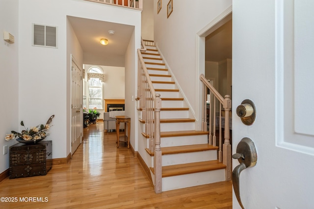 entrance foyer with a fireplace, visible vents, light wood-type flooring, baseboards, and stairs