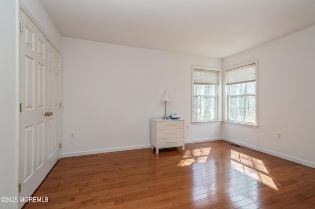 empty room featuring baseboards, visible vents, and hardwood / wood-style floors