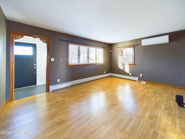 interior space with baseboard heating, a wealth of natural light, light hardwood / wood-style flooring, and a wall mounted AC