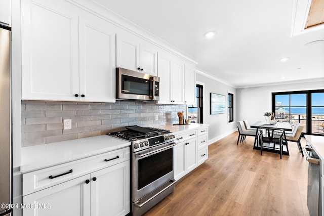 kitchen with crown molding, stainless steel appliances, light wood-type flooring, and white cabinets