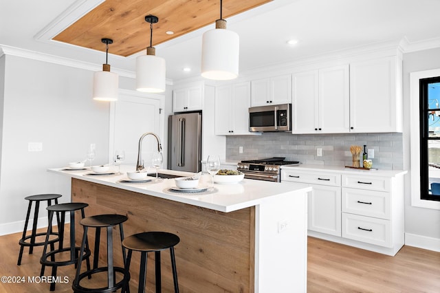 kitchen with high end appliances, decorative light fixtures, tasteful backsplash, and white cabinets