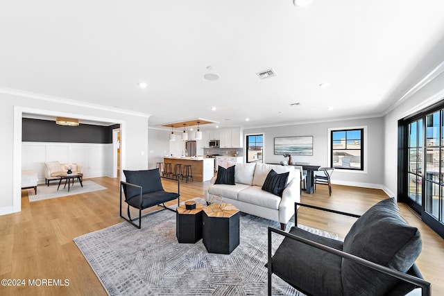 living room with ornamental molding and light hardwood / wood-style flooring