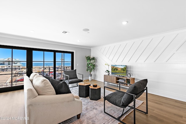 living room with hardwood / wood-style floors, a water view, and crown molding