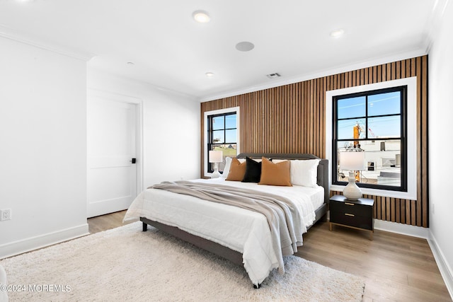 bedroom with ornamental molding, multiple windows, and wood-type flooring