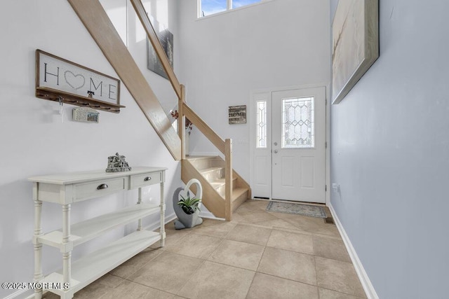 foyer entrance featuring a high ceiling, light tile patterned flooring, and plenty of natural light