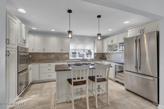 kitchen with appliances with stainless steel finishes, wine cooler, white cabinets, and a kitchen island