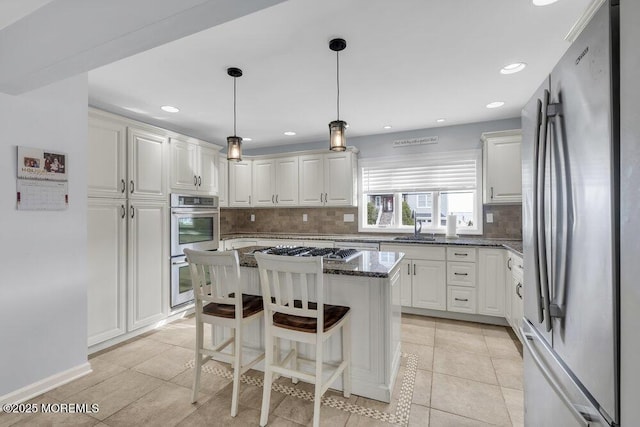 kitchen featuring white cabinets, a kitchen breakfast bar, stainless steel appliances, and a center island