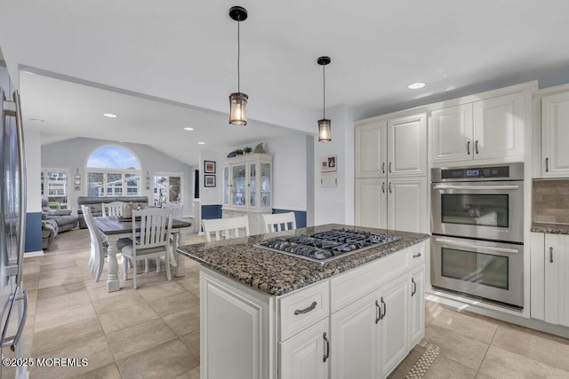 kitchen with tasteful backsplash, lofted ceiling, dark stone countertops, white cabinetry, and stainless steel appliances