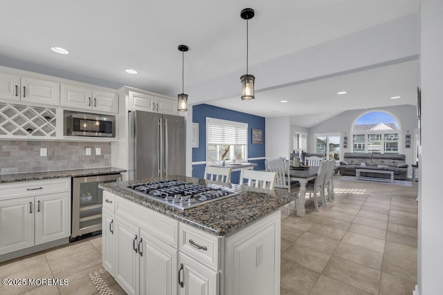 kitchen featuring white cabinets, beverage cooler, a center island, stainless steel appliances, and backsplash