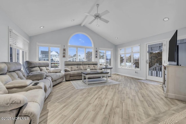 living room featuring ceiling fan, vaulted ceiling with beams, a healthy amount of sunlight, and light hardwood / wood-style floors