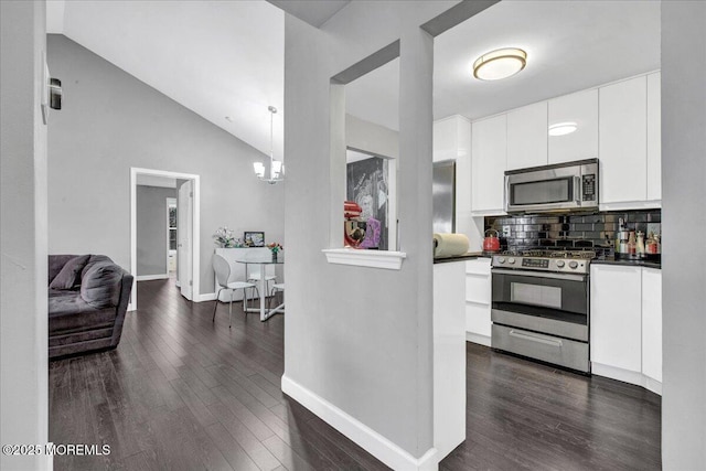 kitchen featuring dark wood-type flooring, pendant lighting, stainless steel appliances, tasteful backsplash, and white cabinetry