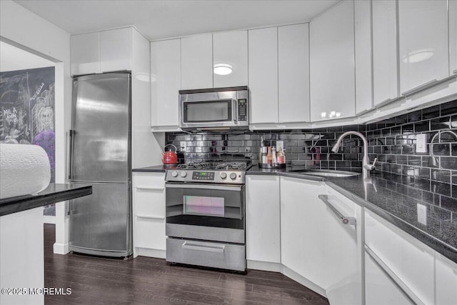 kitchen with sink, white cabinetry, backsplash, dark hardwood / wood-style floors, and appliances with stainless steel finishes