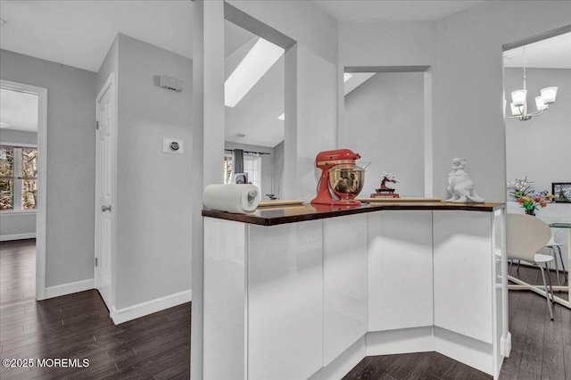 kitchen with dark hardwood / wood-style flooring, white cabinetry, a notable chandelier, and kitchen peninsula