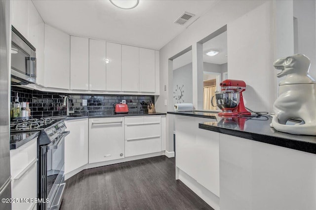 kitchen with decorative backsplash, dark hardwood / wood-style flooring, white cabinetry, appliances with stainless steel finishes, and sink