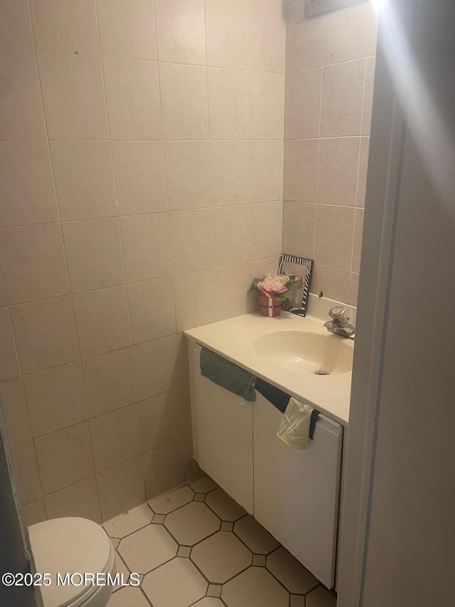 bathroom featuring tile walls, toilet, and vanity