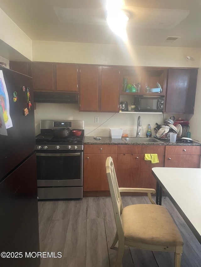 kitchen featuring sink, fridge, stainless steel range with gas cooktop, and dark hardwood / wood-style floors