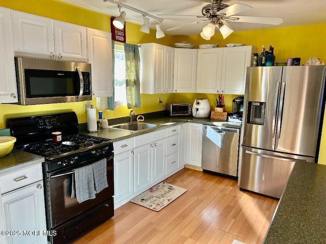 kitchen featuring white cabinets, light wood-type flooring, appliances with stainless steel finishes, and sink