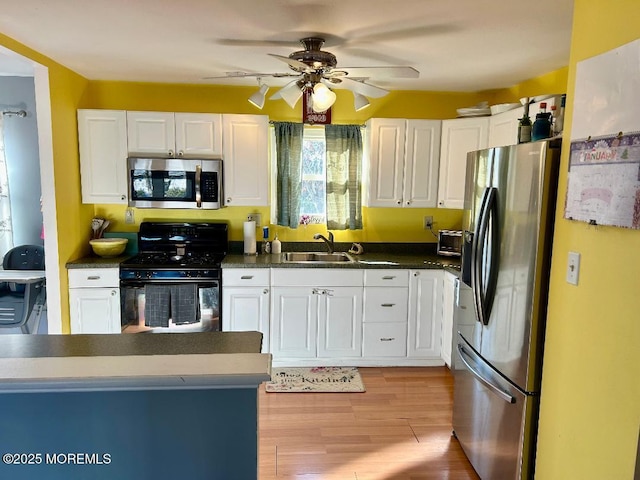 kitchen with ceiling fan, white cabinets, appliances with stainless steel finishes, and sink