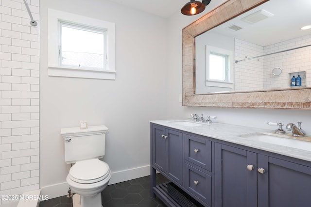 bathroom featuring toilet, vanity, tile patterned floors, and tiled shower