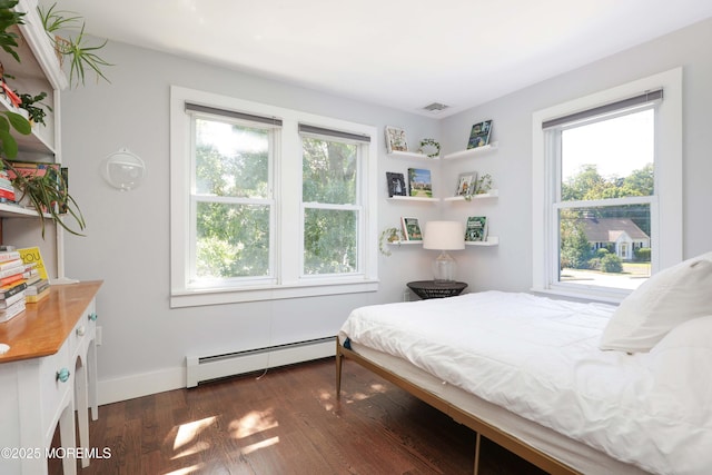 bedroom with baseboard heating, multiple windows, and dark hardwood / wood-style floors