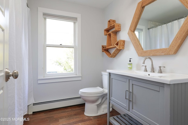 bathroom featuring vanity, hardwood / wood-style floors, baseboard heating, and a wealth of natural light