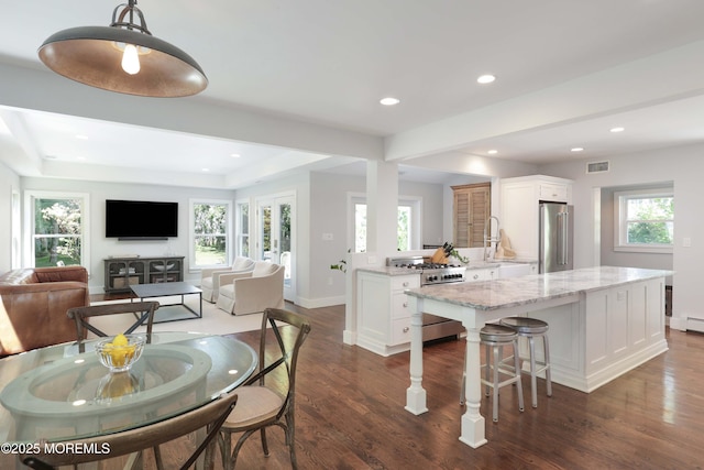 kitchen featuring white cabinets, hanging light fixtures, light stone counters, and high quality appliances