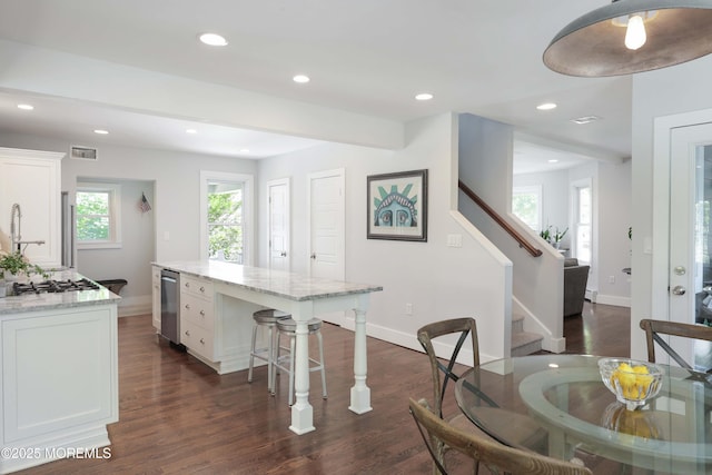 kitchen featuring a center island, stainless steel gas cooktop, light stone countertops, dark hardwood / wood-style floors, and white cabinetry