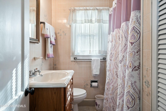 bathroom with toilet, tile walls, and vanity