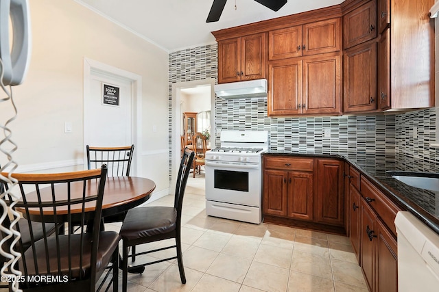 kitchen featuring white appliances, dark stone counters, decorative backsplash, ceiling fan, and light tile patterned floors