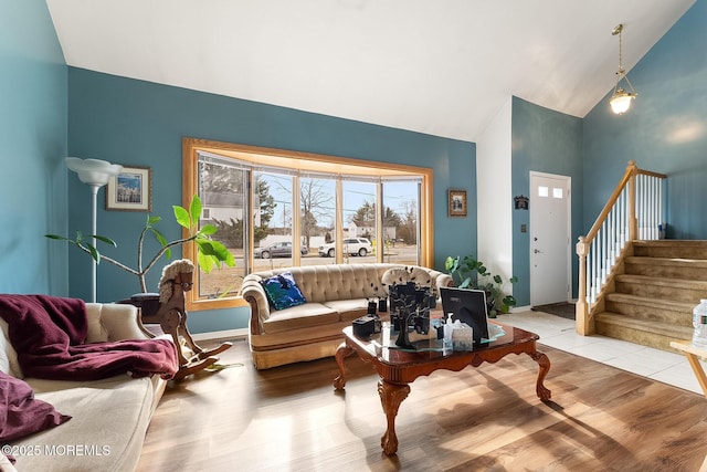 living area featuring high vaulted ceiling, light tile patterned floors, baseboards, and stairs