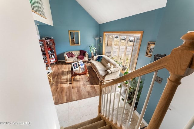 tiled living room featuring high vaulted ceiling and stairway