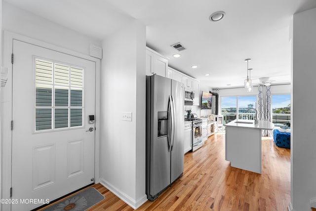 kitchen featuring kitchen peninsula, light wood-type flooring, white cabinets, appliances with stainless steel finishes, and a kitchen breakfast bar