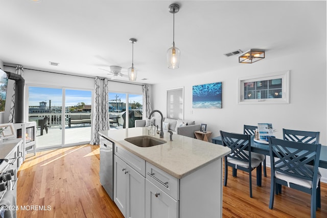 kitchen with dishwasher, decorative light fixtures, a center island with sink, ceiling fan, and sink