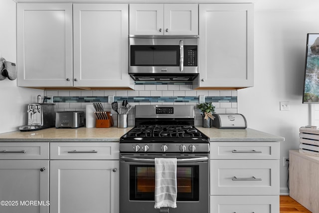 kitchen featuring decorative backsplash, white cabinetry, and appliances with stainless steel finishes